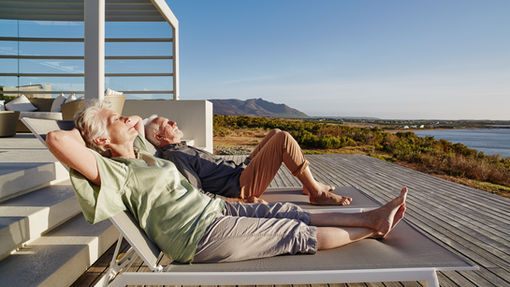 A couple relaxing on a beachside deck, symbolizing early retirement and financial freedom, aligning with the concept of using the Rule of 55 to enjoy life after leaving work at age 55.