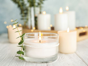 White Candles Burning on a White Wood Table with Eucalyptus