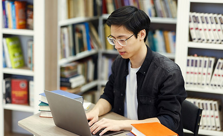 A guy using a computer in a library