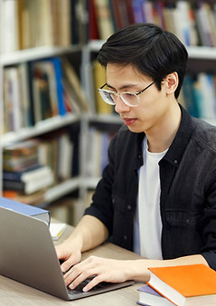 A guy using a computer in a library