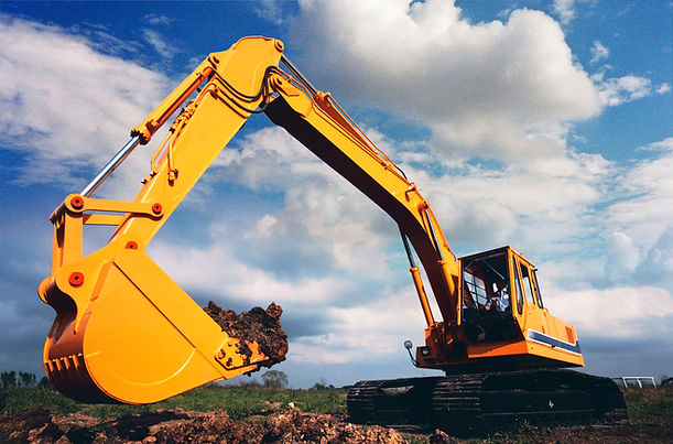 A bright orange excavator is digging into a mound of earth under a partly cloudy sky