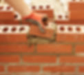 Bricklayer inserts a half brick into a wall