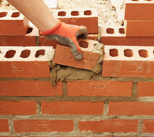 Bricklayer inserts a half brick into a wall