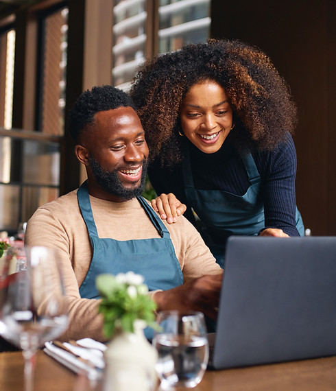 A husband and wife team happily review their marketing analytics inside their restaurant.