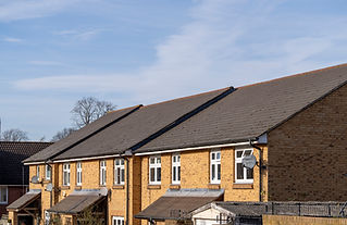 Dark tiled rooftops of residential houses with tan brick walls under a blue sky