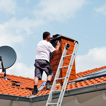 Man covering chimney with roofing shingles