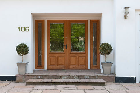 Wooden front door with glass panels and potted topiary trees at a house entrance in Benfleet Essex