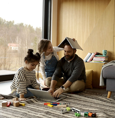 Minneapolis dad working on laptop while kids play, showcasing safe home environment with agency-vetted nanny support.