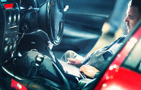 Car mechanic running diagnostics with laptop and OBD software