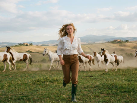 Woman running in field of horses