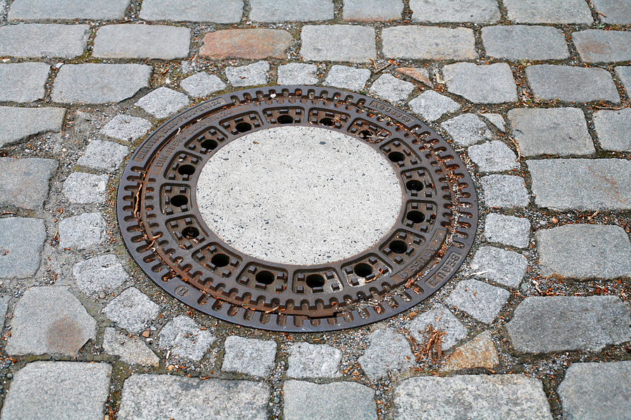 Cast iron street manhole cover set in cobblestone paving