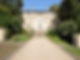 Grand historic white stately building with a long sweeping gravel driveway approach