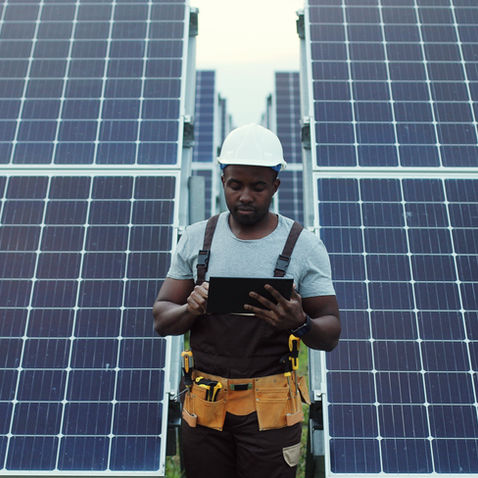 Person in hard hat and construction uniform in front of solar panels