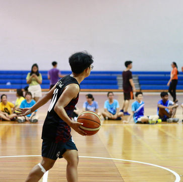 Basketballspieler dribbelt auf dem Feld vor sitzenden Zuschauern.