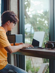 Person Working On Laptop At Window Seat