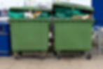 close-up image of two green garbage bins filled with waste