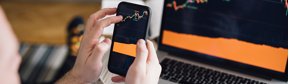 Personne consultant des graphiques boursiers sur smartphone et ordinateur, illustrant le suivi d'investissements via un Plan