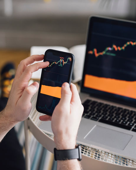 Alguien observa sus finanzas en sendos gráficos en su ordenador y en su smartphone.