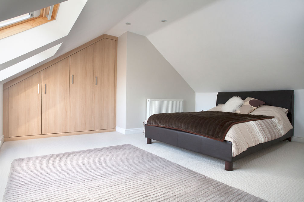 Fitted attic wardrobe with sloped ceiling storage and bedroom furnishings.