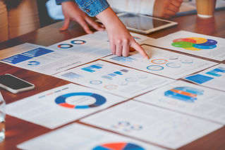 Close-up of hands pointing to various colorful printed financial charts and graphs