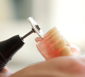 Dental technician using a tool to precisely craft a custom dental crown model