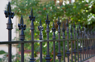 Black metal spiked residential fence diminishing to soft focus in the distance