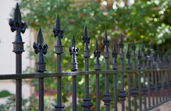 Black metal spiked residential fence diminishing to soft focus in the distance