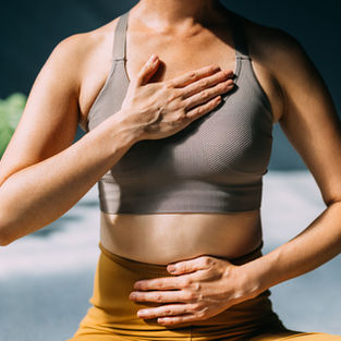 Woman with one hand on her chest and her other on her belly, meditating and self-regulating.