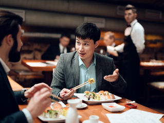 Two people having an engaged conversation over a meal, with one person gesturing as he speaks and the other listening.