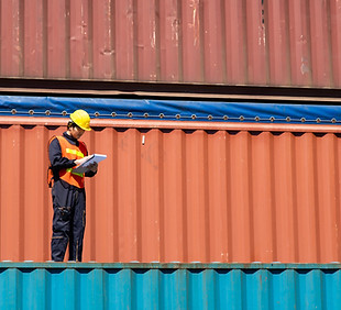 Worker Inspecting Shipping Containers