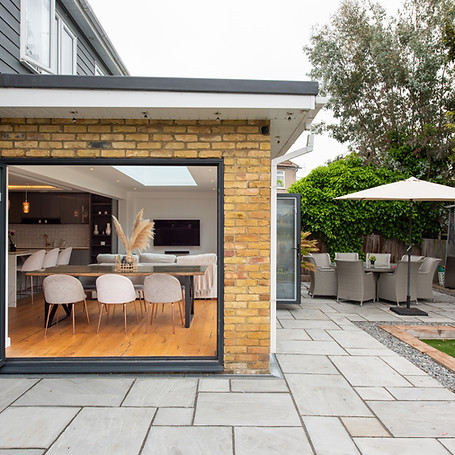 A general interior view of a Home extension with open patio doors, garden furniture table
