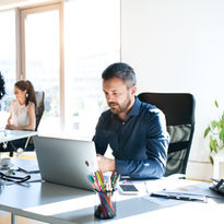 3 Mitarbeiter sitzen am Schreibtisch und beraten sich