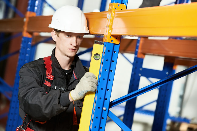 Worker aligning warehouse racking with a yellow level.