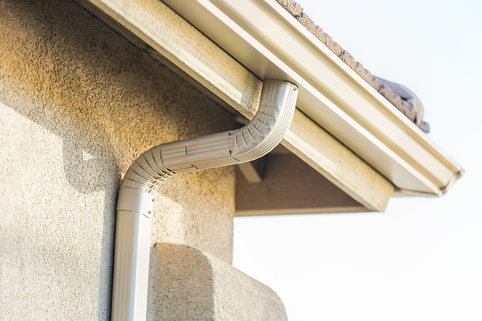 Close-up of a beige, textured wall with a white rain gutter system