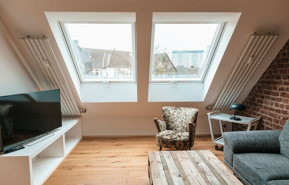 Modern loft living room with skylights, floral armchair, and exposed brick wall