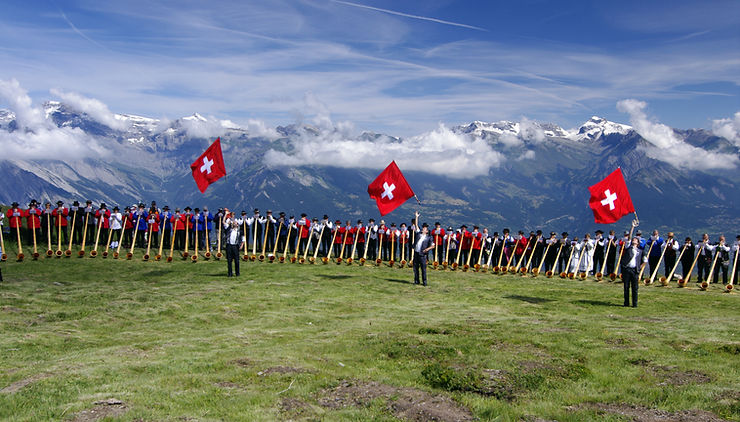 Switzerland - open field with mountain views - people shaking flags