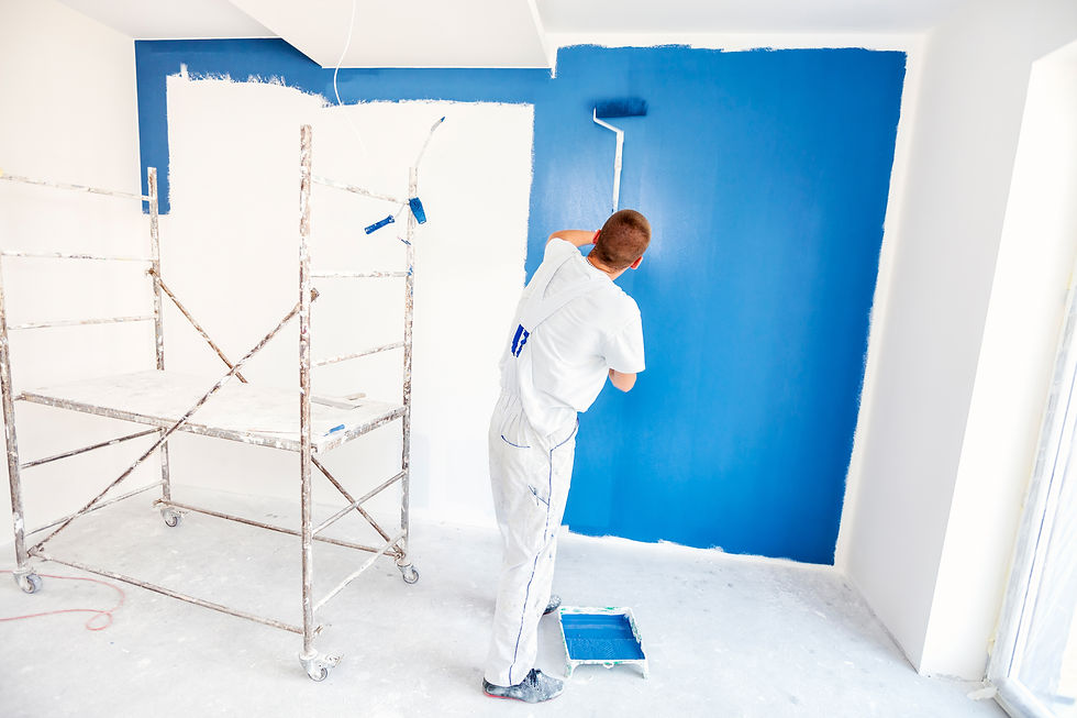 Professional painter using a roller to apply blue paint on a tall wall
