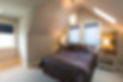 Loft with a bed and tables with lamps