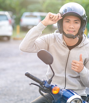 ชายวัยรุ่นใส่หมวกนิรภัยยืนคร่อมมอเตอร์ไซค์