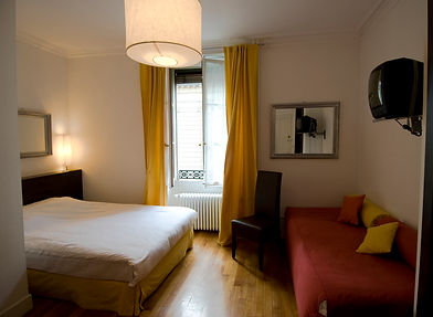 Small hotel or guest room with a double bed, sofa bed, TV, mirror, and bright yellow window curtains