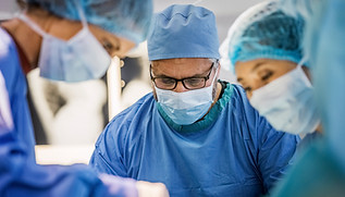 Team of surgeons operating girl at hospital. Multi-ethnic doctors are performing surgery