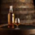 Unlabelled whisky bottle and glass on barrel