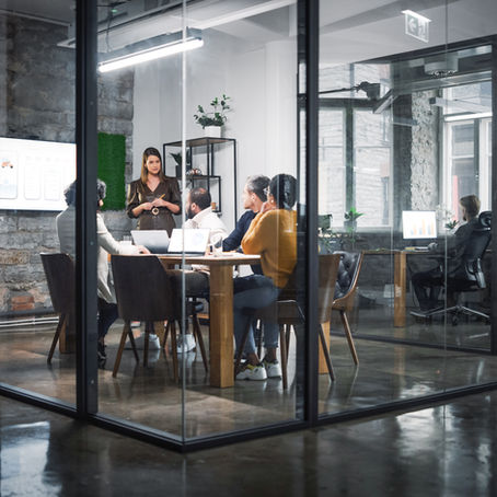 A modern workplace setting with employees seated in a meeting room - illustrating the environment where workplace mental health support can be embedded and normalised.