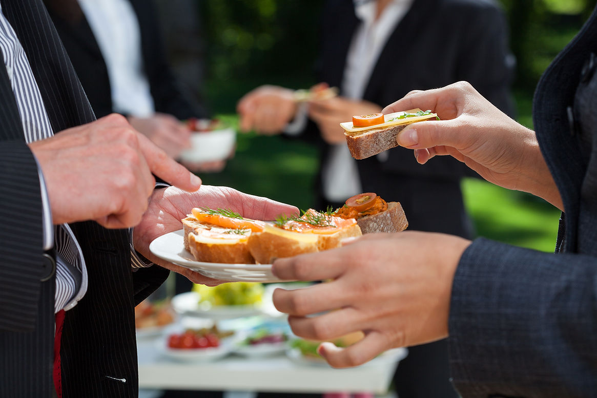Close up of business professionals holding colourful gourmet canapes on a platter at a corporate outdoor event