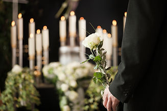 Man with white roses at urn funeral