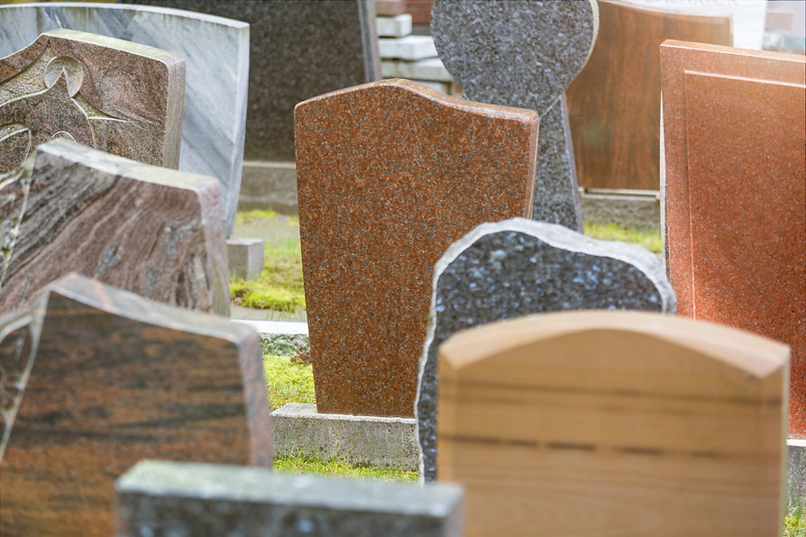 Collection of various polished granite headstones in different shapes and colours displayed in a cemetery