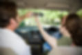 Close-up view of a teen girl and her driving instructor adjusting the rearview mirror