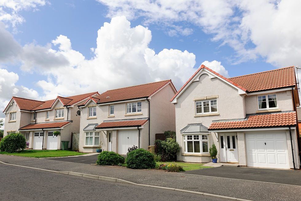 Row of white suburban houses with red tile roofs under a cloudy sky