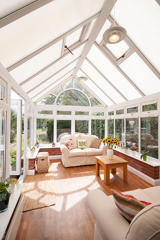 Bright conservatory with white-framed windows and a glass roof