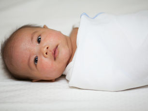 Baby swaddled and looking at viewer.